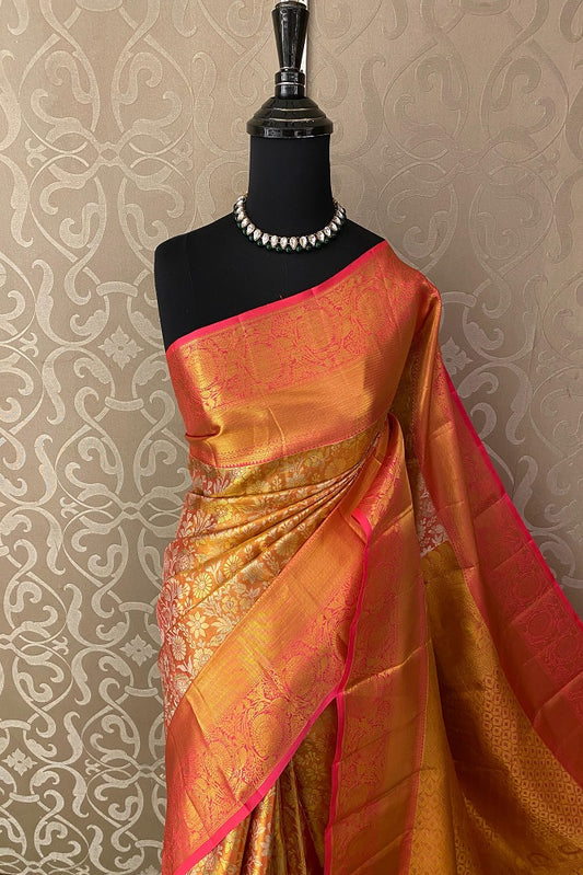 Golden orange Kanjeevaram silk saree with intricate designs, paired with an unstiched blouse for traditional Indian wear.