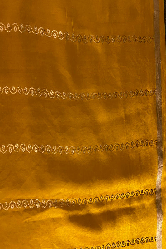 Mustard yellow Mashru silk Banarasi handloom saree with intricate gold zari work and matching unstiched blouse, traditional Indian wear.
