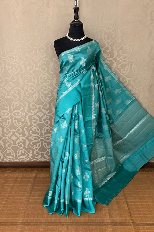 Turquoise Chiniya silk saree with hand-woven butas, traditional wear by Saarang Sarees, featuring intricate craftsmanship and vibrant design.