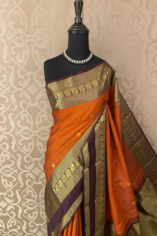 Orange pure Kanjeevaram silk saree with intricate gold zari work and matching unstiched blouse, traditional South Indian attire.