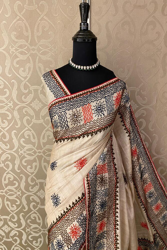 Beige Tussar Lambani and Kutch work saree with unstitched blouse from Saarang Sarees, showcasing traditional embroidery and intricate details.