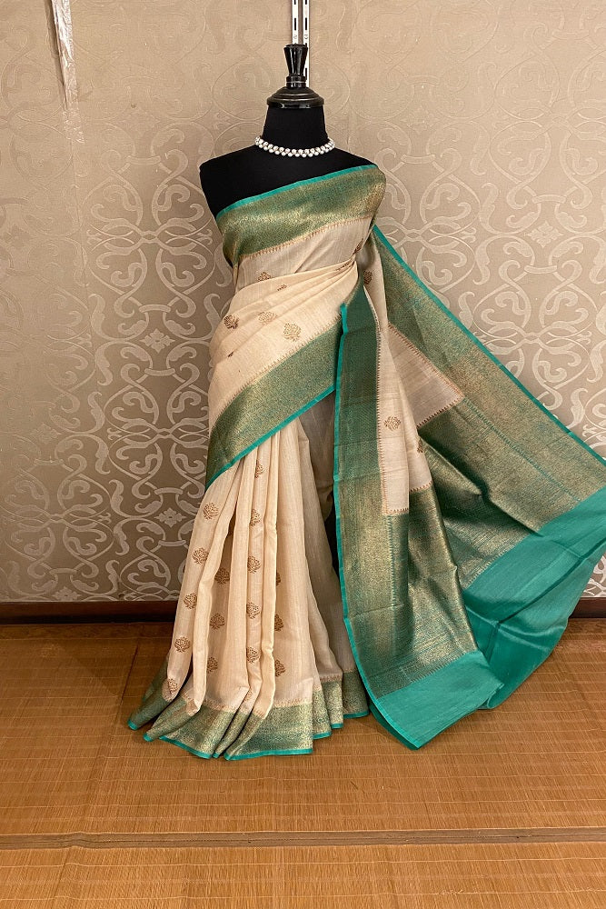 Offwhite Tussar Banarasi silk saree by Saarang Sarees with hand-woven motifs and matching unstitched blouse, traditional wear.