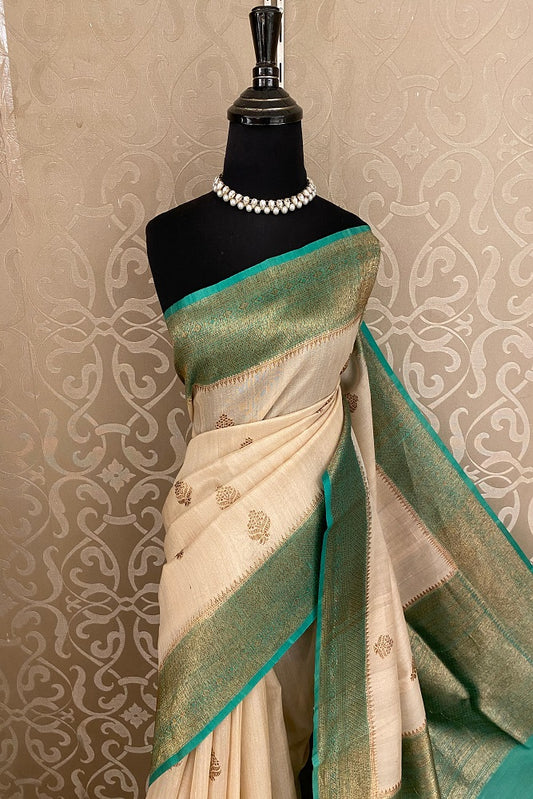 Offwhite Tussar Banarasi silk saree by Saarang Sarees with hand-woven motifs and an unstiched blouse, traditional wear.