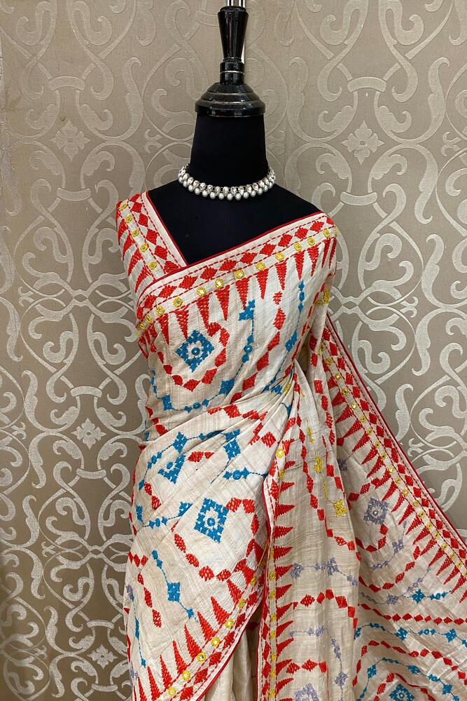 Beige Tussar Lambani and Kutch work saree with stitched blouse, traditional wear by Saarang Sarees, displayed on a hanger.