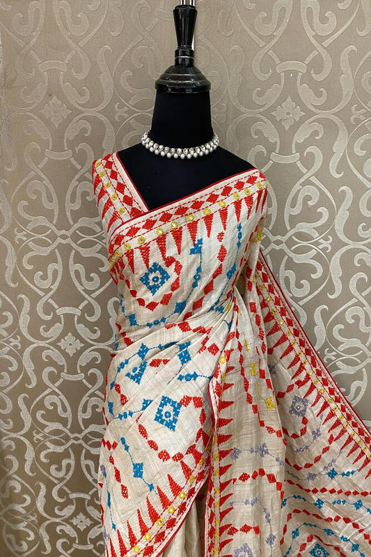 Beige Tussar Lambani and Kutch work saree with stitched blouse, traditional wear by Saarang Sarees, displayed on a hanger.