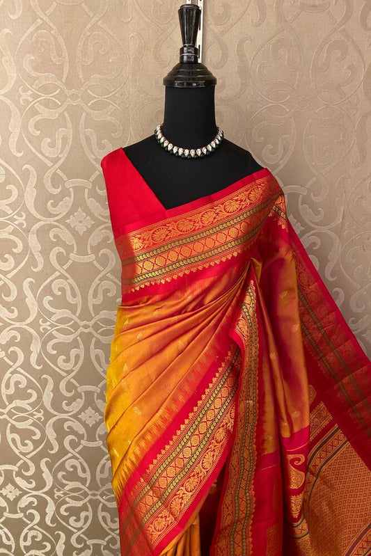 Yellow Gadwal silk saree with traditional orange and gold designs, paired with an unstitched blouse, by Saarang Sarees.