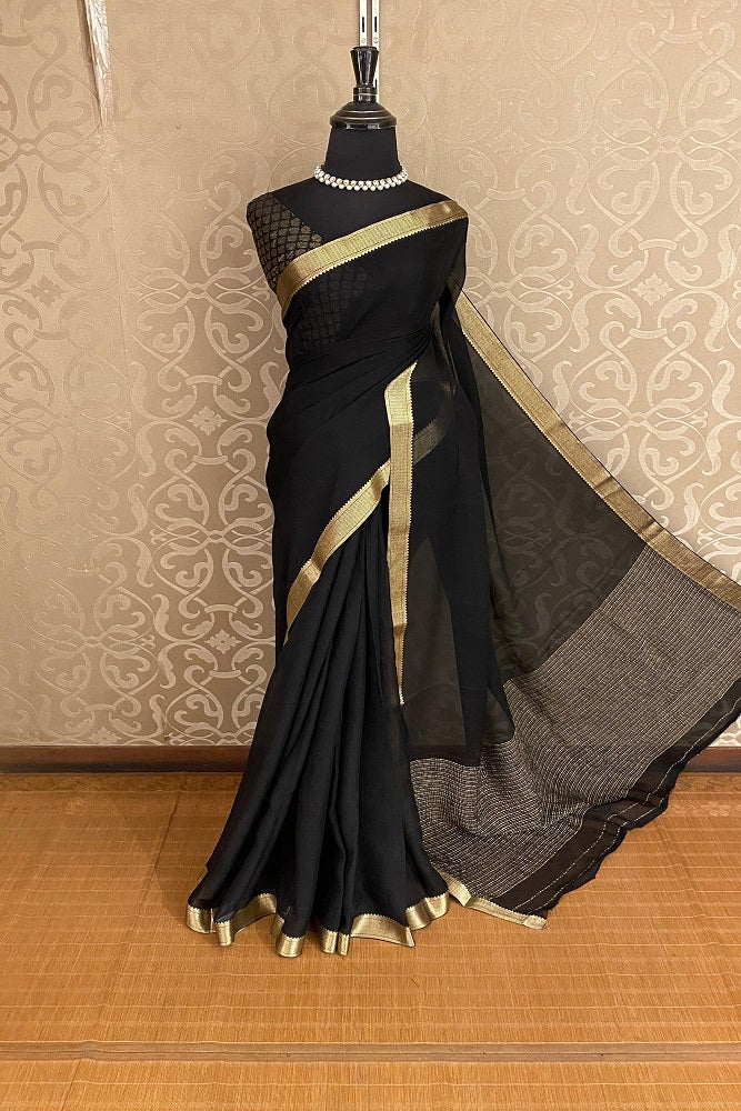 Black chiffon saree with zari border and unstiched blouse, elegant party wear by Saarang Sarees, displayed on a hanger.