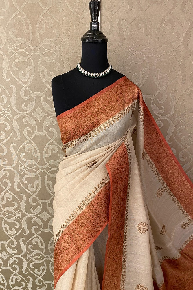 Offwhite Tussar Banarasi silk saree by Saarang Sarees with handwoven motifs and an unstiched blouse for traditional wear.