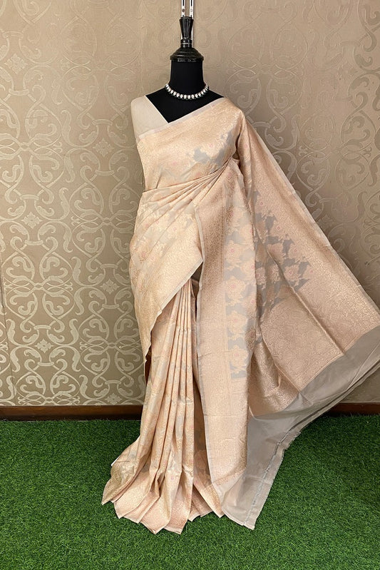 Light peach Uppada Banarasi saree with intricate gold zari work and matching unstiched blouse, traditional Indian wear by Saarang Sarees.