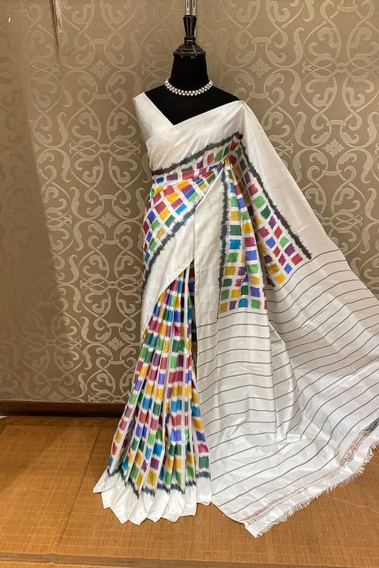 White and multi-colored Pochampally Ikat silk saree by Saarang Sarees with an unstiched blouse, traditional Indian wear with intricate patterns.